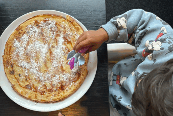 Kind aan tafel met pannenkoek