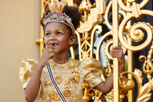 Meisje in gouden kleren bij een goud hek