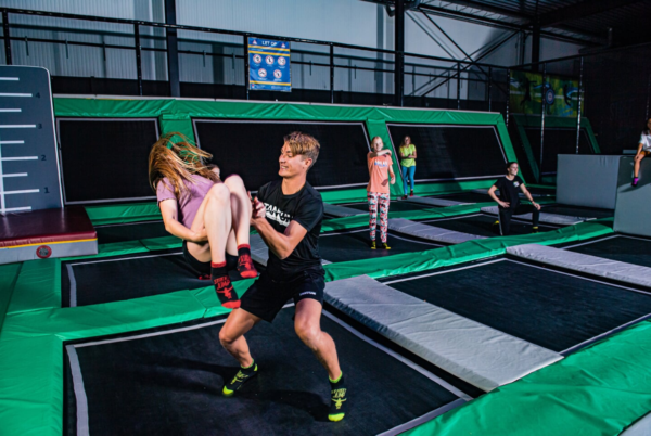 meisje dat geholpen wordt met het maken van een salto op een trampoline