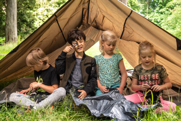 vier kinderen in een tent in de natuur