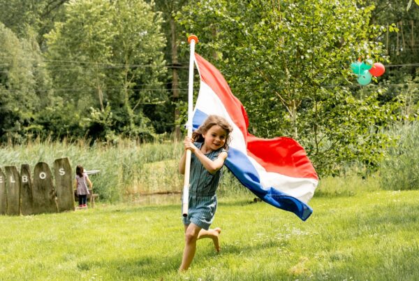 Met met Nederlandse vlag op blote voeten door het gras tijdens Koningsdag