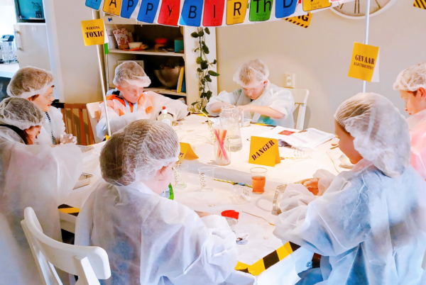 Kinderen aan tafel met feestje en laboratorium kleding aan