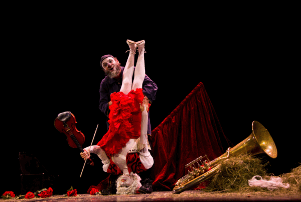 2 clowns op een podium. 1 op haar kop, de andere houdt haar vast